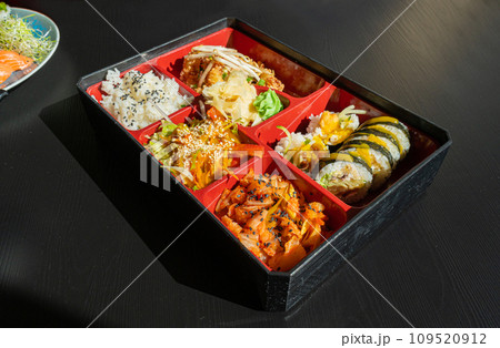 Japanese Lunch in Bento Box with Deep-Fried Squid Rings, Sushi Rolls, Salad, Rice, Pickled Ginger Japanese Lunch in Bento Box with Deep-Fried Squid Rings, Sushi Rolls, Salad, Rice, Pickled Ginger 109520912