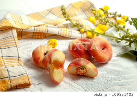 Halves and three whole saturn peaches or flat peach on white wooden background.. 109521402