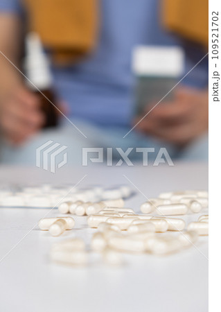 Pills on the table and a sick person with medicines in the hands. 109521702