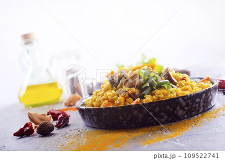 Pilaf, a dish of rice, chicken, carrots with spices and dried cranberries on a black plate 109522741