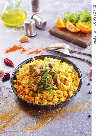 Pilaf, a dish of rice, chicken, carrots with spices and dried cranberries on a black plate 109522742
