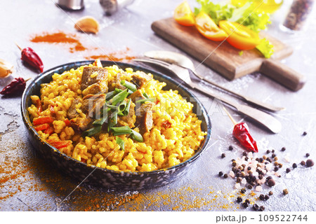 Pilaf, a dish of rice, chicken, carrots with spices and dried cranberries on a black plate 109522744