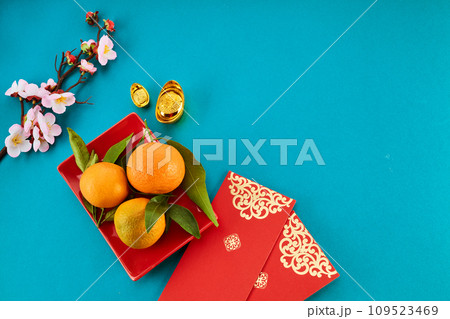 Chinese New Year. Red packet envelope, flowers, mandarins, festival decorations on teal color background. Flat lay, top view. 109523469