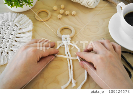 Close-up of women's hands, which are engaged in weaving from natural cotton twine. textile produced using macrame technique 109524578