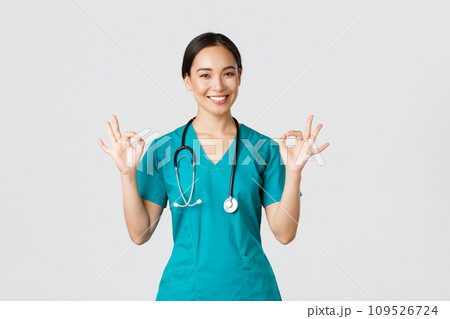 Covid-19, healthcare workers, pandemic concept. Professional confident asian female doctor, intern in scrubs assure patients everything good, showing okay gesture satisfied, smiling pleased Covid-19, healthcare workers, pandemic concept. Professional confident asian female doctor, intern in scrubs assure patients everything good, showing okay gesture satisfied, smiling pleased 109526724