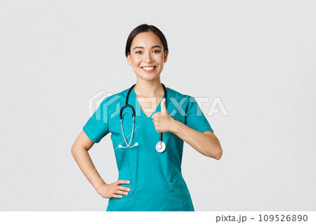 Covid-19, healthcare workers, pandemic concept. Smiling upbeat, confident female asian nurse in scrubs have all under control, show thumbs-up in approval, guarantee quality of service in clinic Covid-19, healthcare workers, pandemic concept. Smiling upbeat, confident female asian nurse in scrubs have all under control, show thumbs-up in approval, guarantee quality of service in clinic 109526890