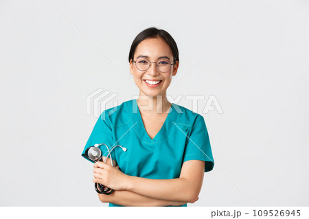 Covid-19, coronavirus disease, healthcare workers concept. Confident happy asian female physician, doctor in glasses, cross arms chest and smiling, holding stethoscope for examination 109526945