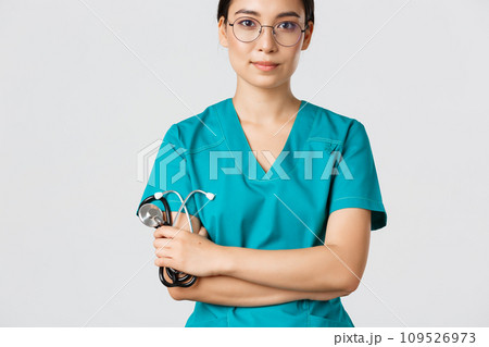 Covid-19, coronavirus disease, healthcare workers concept. Confident smiling professional asian doctor in glasses, cross arms chest, wearing scrubs and holding stethoscope, white background Covid-19, coronavirus disease, healthcare workers concept. Confident smiling professional asian doctor in glasses, cross arms chest, wearing scrubs and holding stethoscope, white background 109526973