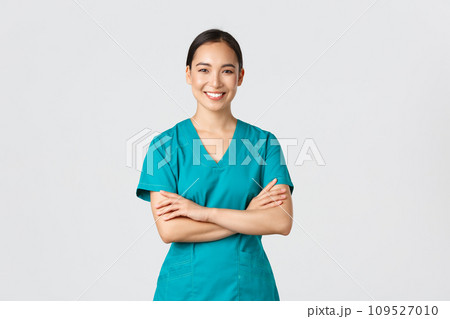 Covid-19, healthcare workers, pandemic concept. Confident smiling asian doctor, female nurse in scrubs standing determined, cross arms chest over white background. Doctor ready for shift in clinic Covid-19, healthcare workers, pandemic concept. Confident smiling asian doctor, female nurse in scrubs standing determined, cross arms chest over white background. Doctor ready for shift in clinic 109527010