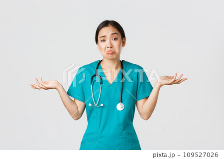 Covid-19, healthcare workers, pandemic concept. Portrait of clueless asian female nurse, woman doctor shrugging and spread hands sideways unaware, dont know, cant help, white background 109527026