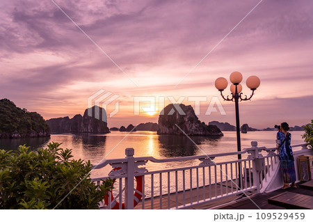 ベトナム　ハロン湾クルーズのクルーズ船の船上デッキから夕陽の写真を撮る女性 109529459