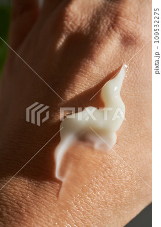 A smear of white moisturizer or sunscreen on a woman's hand. A smear of white moisturizer or sunscreen on a woman's hand. 109532275
