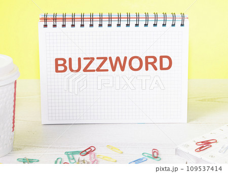 Buzzword the word is written on a blank sheet in a notebook standing on a table on a yellow background Buzzword the word is written on a blank sheet in a notebook standing on a table on a yellow background 109537414