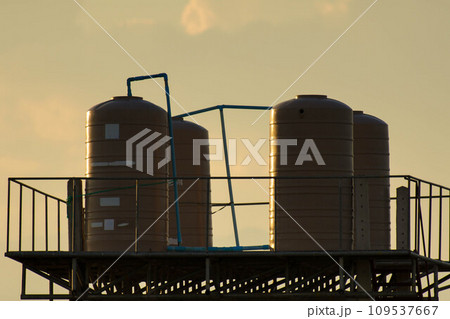 Cream Color Outdoor Plastic Water Tank on Tower. Plastic water tank installed high to let the water down lower. Water tank outside the house. 109537667