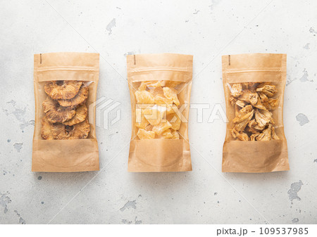 Packages with dried sweet pineapple slices and chips on light background. 109537985