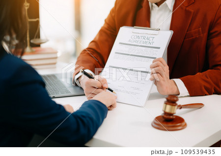 Two lawyers are discussing about contract paper, law matters determination, pointing.law and hammer on the table Two lawyers are discussing about contract paper, law matters determination, pointing.law and hammer on the table 109539435
