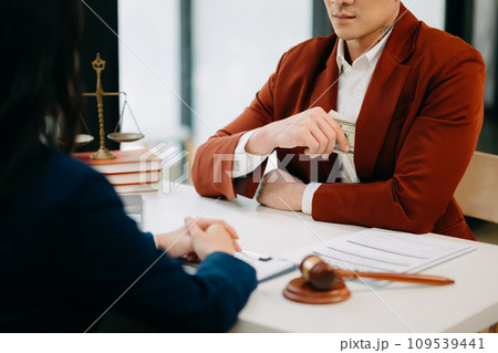 justice and law concept.passing bribe money in the envelop at lawyer office. businessman hand taking bribe money from female justice and law concept.passing bribe money in the envelop at lawyer office. businessman hand taking bribe money from female 109539441