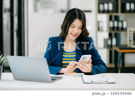 Young beautiful woman typing on tablet and laptop while sitting at the working white table office Young beautiful woman typing on tablet and laptop while sitting at the working white table office 109539486
