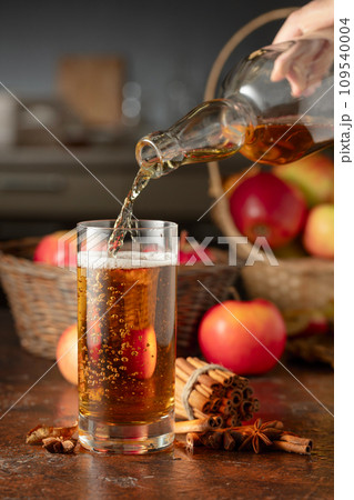 Apple cider is poured from a bottle into a glass. 109540004