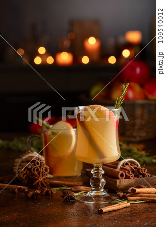 Mulled cider with apples, cinnamon, rosemary, and anise on a background of burning candles. 109540012