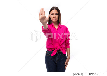 young confident caucasian brunette woman in bright pink shirt shows stop gesture 109542607