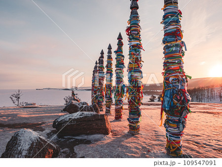 Traditional buryat shaman sacred pillars with colorful ribbons in winter at sunset, cape Burkhan, Olkhon island. Winter Baikal. 109547091