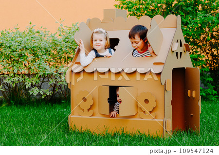 Children are playing in cardboard kid house. Child having fun outdoors. 109547124