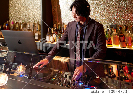 クラブで演奏するヘッドフォンの若い男性DJ 109548233