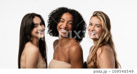 Female models of different ages celebrating their natural bodies in a studio. Three confident and happy women smiling cheerfully. Women standing together against a studio background. 109548549