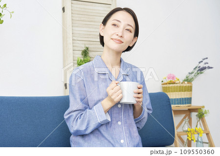 自宅でパジャマを着てマグカップを持って寛ぐ中年女性 109550360