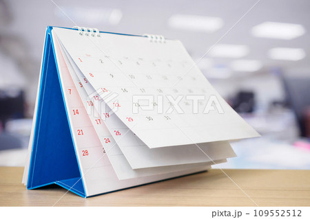Calendar page flipping sheet on table with blurred office interior background business schedule planning appointment meeting concept 109552512