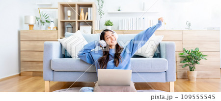 Young asian woman in good spirits working on laptop at home Young asian woman in good spirits working on laptop at home 109555545