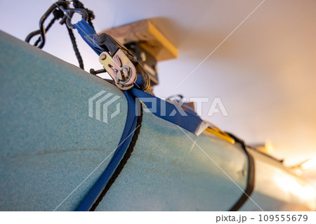 Selective focus on the side of a kayak that has used a Hoist and pulley system to store on the ceiling of a garage. 109555679