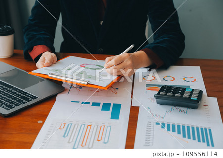 Group of confident business people point to graphs and charts to analyze market data, balance sheet, account, net profit to plan new sales strategies to increase production capacity. Group of confident business people point to graphs and charts to analyze market data, balance sheet, account, net profit to plan new sales strategies to increase production capacity. 109556114