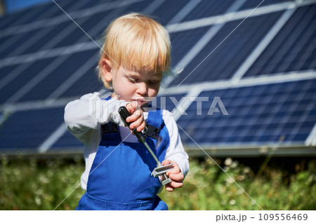 Little child learning how to use screwdriver on background of solar panels. Curious kid interested in repairing. Blond toddler tries to tighten the screw. Little child learning how to use screwdriver on background of solar panels. Curious kid interested in repairing. Blond toddler tries to tighten the screw. 109556469