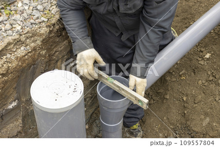 住宅の排水を下水道につなげる配管工事する人物 109557804