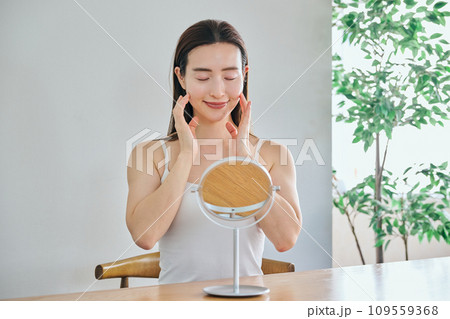 顔をマッサージして肌のお手入れをする30代女性 109559368