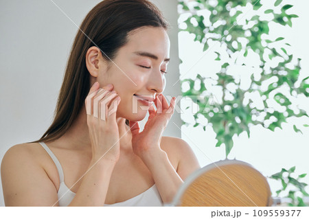 顔をマッサージして肌のお手入れをする30代女性 顔をマッサージして肌のお手入れをする30代女性 109559377