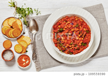 traditional chakalaka, refreshing spicy tomato bean relish in white bowl on white wooden table with spoon and crackers traditional chakalaka, refreshing spicy tomato bean relish in white bowl on white wooden table with spoon and crackers 109559390