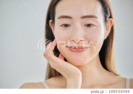 顔をマッサージして肌のお手入れをする30代女性 109559394