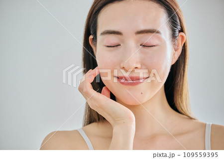 顔をマッサージして肌のお手入れをする30代女性 109559395