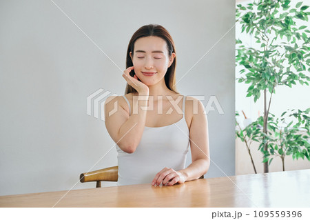 顔をマッサージして肌のお手入れをする30代女性 109559396