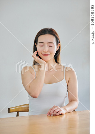 顔をマッサージして肌のお手入れをする30代女性 109559398