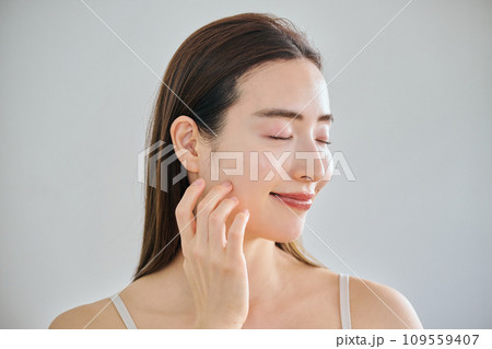 顔をマッサージして肌のお手入れをする30代女性 109559407