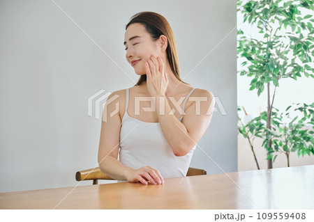 顔をマッサージして肌のお手入れをする30代女性 109559408