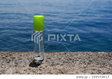 Organic cosmetic glass bottle with with sea minerals. Skincare cosmetic product staying on the stone, blue water background 109559617