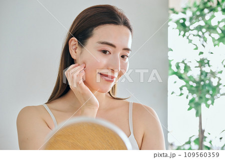 顔をマッサージして肌のお手入れをする30代女性 109560359