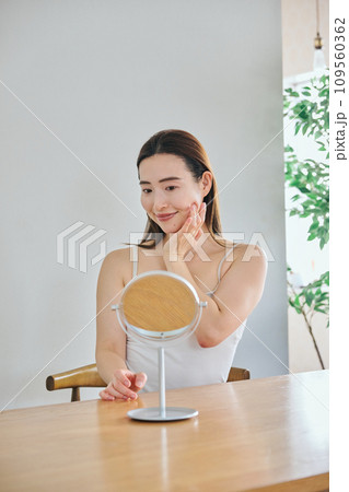 顔をマッサージして肌のお手入れをする30代女性 109560362