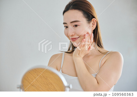 顔をマッサージして肌のお手入れをする30代女性 109560363