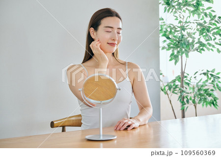 顔をマッサージして肌のお手入れをする30代女性 109560369